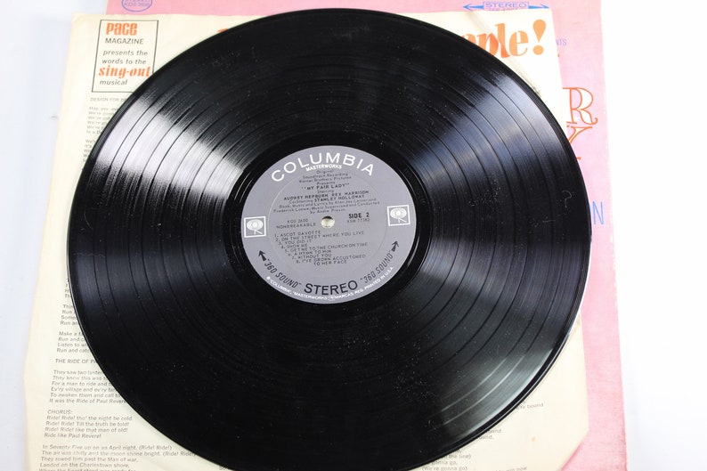 May include: A black vinyl record with a Columbia Records label. The label features the title "My Fair Lady" and the song titles "Wouldn't It Be Loverly" and "I Could Have Danced All Night".