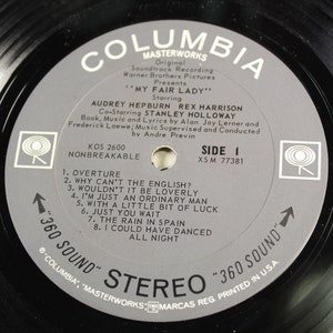May include: A gray vinyl record with the title "My Fair Lady" starring Audrey Hepburn and Rex Harrison. The record is from Columbia Masterworks and is a 360 Sound Stereo record. The record is side one and has the song titles listed on the label.