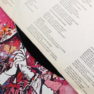May include: A vintage vinyl record with a colorful illustration of people and a car on the cover. The record is titled "Which Way America?" and includes lyrics about equality and unity. The lyrics include the phrase "What color is God's skin?"