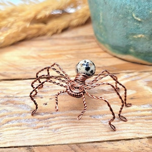 Puede incluir: Una escultura de araña de alambre de cobre con una piedra de jaspe dalmata en blanco y negro para la cabeza.