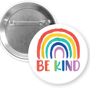 May include: A white button with a rainbow and the text "BE KIND" in rainbow colors.