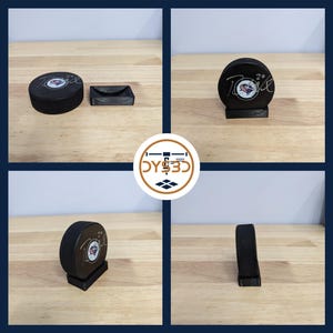 May include: A black hockey puck display stand with a black hockey puck featuring a team logo and a signature. The puck is on a black base with a raised platform.