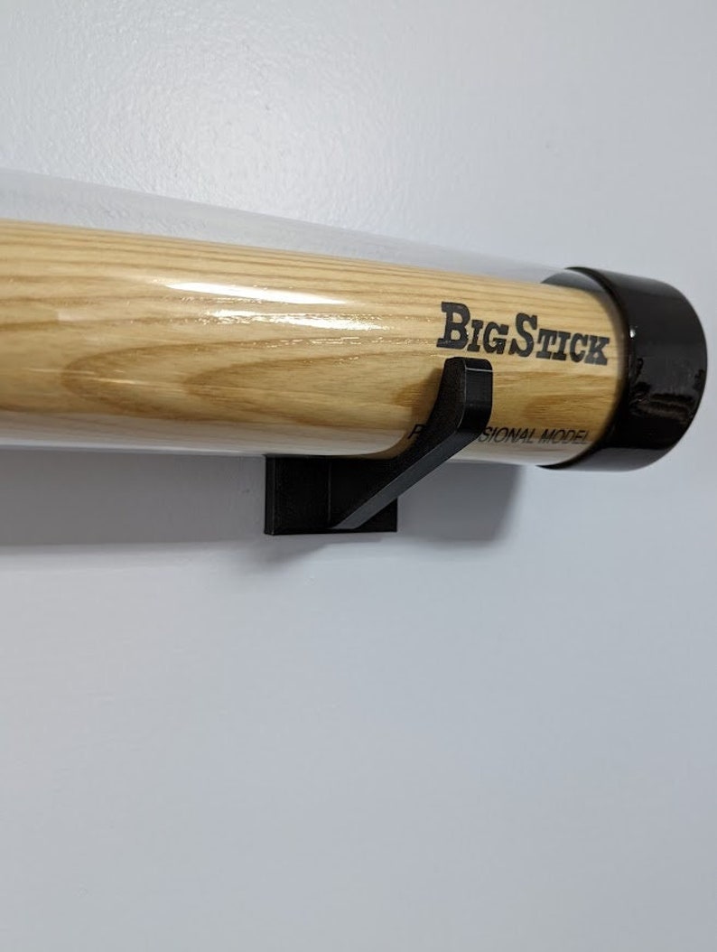 K&ouml;nnte beinhalten: Ein schwarzer Baseballschl&auml;gerhalter mit einem Holzschl&auml;ger im Inneren. Der Schl&auml;ger ist mit "Big Stick Professional Model" beschriftet.
