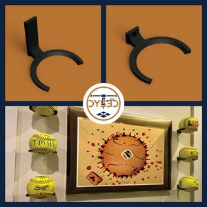 May include: Black 3D printed softball display stand with a curved design. The stand is mounted on a wall and holds a softball. The stand is shown with several other softball displays holding softballs with different team names.