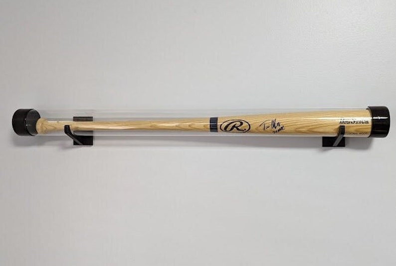 K&ouml;nnte beinhalten: Ein Holz-Baseballschl&auml;ger mit einem schwarz-wei&szlig;en Logo und einer Unterschrift, ausgestellt in einem durchsichtigen Plastikrohr mit schwarzen Endkappen und an einer Wand montiert.