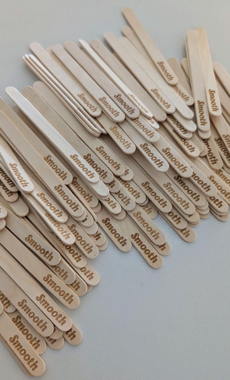 May include: A pile of light-coloured wooden craft sticks, each engraved with the word "Smooth". The sticks are arranged in a slightly overlapping pattern, creating a textured surface. The overall effect is a natural, neutral aesthetic.