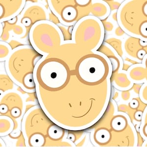 May include: A yellow cartoon character with brown glasses and a smile. The character has pink ears and a brown nose. The character is surrounded by other cartoon characters.