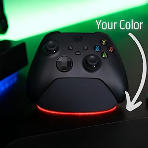 Pode incluir: Um controlador Xbox preto com uma luz vermelha na base. O texto "Your Color" está escrito acima do controlador.