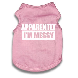 May include: Pink sleeveless dog shirt with the text "APPARENTLY I'M MESSY" in white.