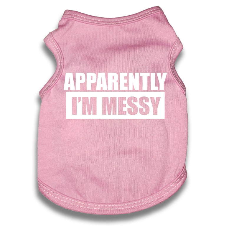 May include: Pink sleeveless dog shirt with the text "APPARENTLY I'M MESSY" in white.