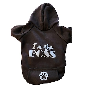May include: Black hooded sweatshirt for dogs with the text "I'm the BOSS" in white lettering and a white paw print on the pocket.