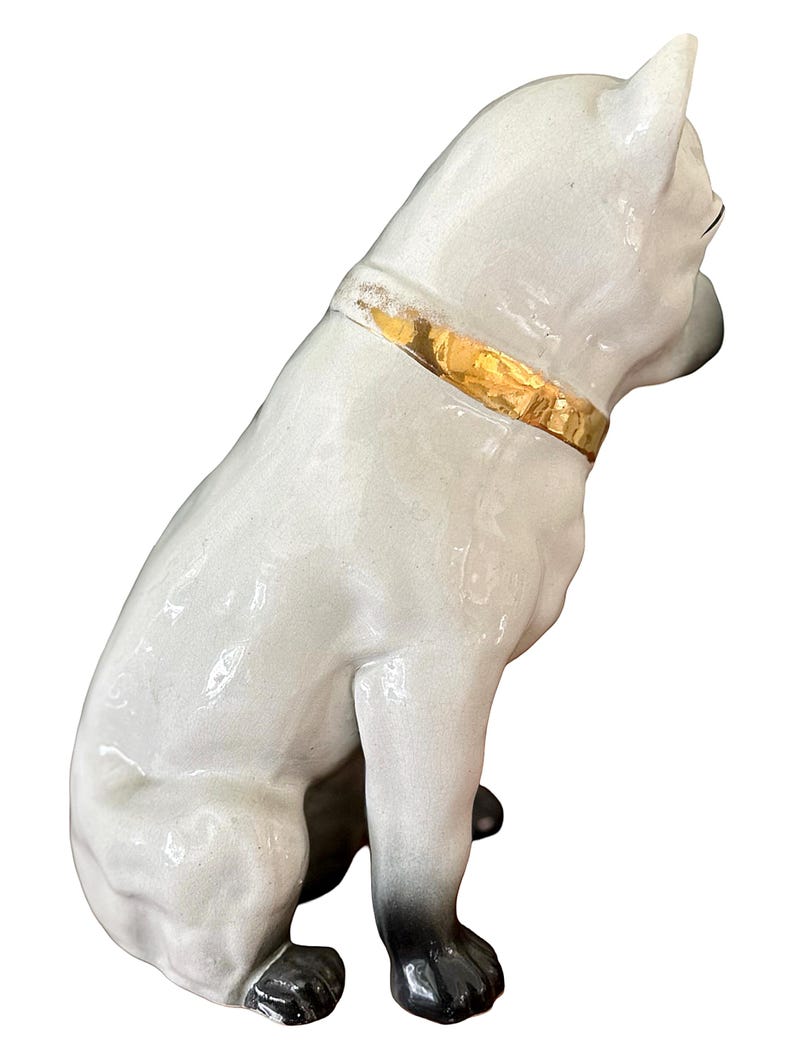 May include: A ceramic dog figurine in a seated position, with a glossy white finish and black paws. The dog wears a gold-colored collar. The figurine is a decorative item.