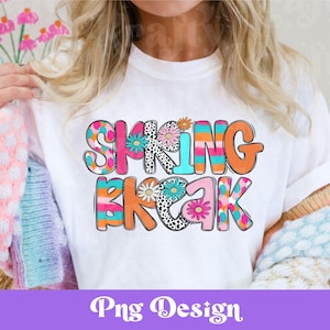 May include: White t-shirt with the words "SPRING BREAK" in colorful, bold letters. The letters are decorated with floral and patterned designs in shades of pink, orange, blue, and black. The shirt has a casual, spring-themed design.