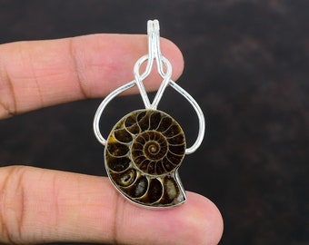 May include: A silver pendant featuring a polished, fossilized ammonite shell. The shell displays a detailed spiral pattern in shades of brown and tan, set within a silver frame. The pendant is designed with a loop for a chain.