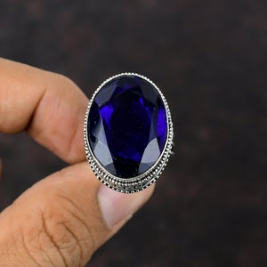 May include: A silver ring with a large, oval-shaped, dark blue gemstone.