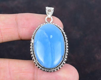 May include: Oval-shaped pendant featuring a light blue gemstone set in a silver-toned metal frame. The gemstone has a smooth, polished surface. The frame has a twisted rope design around the edge and a small loop at the top for a chain.