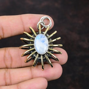 May include: A silver and brass pendant featuring a large oval moonstone set in a sunburst design.