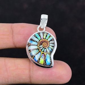 May include: A silver pendant featuring a polished ammonite fossil with iridescent blue, green, and yellow chambers. The fossil is set in a smooth silver frame with a silver bail at the top, showcasing a spiral pattern and natural mineral textures.