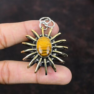 May include: A gold and silver pendant featuring a tiger's eye gemstone set in a sunburst design.