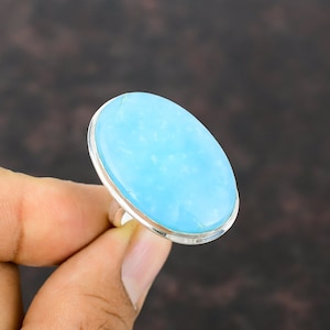 May include: A silver ring with a large oval-shaped light blue gemstone.