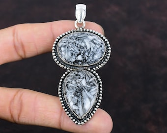 May include: A silver pendant with two black and white marbled stones. The stones are set in silver and the pendant has a bail for attaching to a chain.