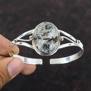 Può includere: Braccialetto in argento con un grande cabochon ovale di pietra macchiata di grigio e nero al centro.