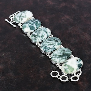 Op de afbeelding: Een zilveren armband met zes ovale, groen-witte agaatstenen. De armband heeft een schuifgesp.