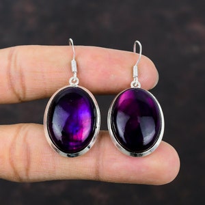 Puede incluir: Un par de pendientes de plata con piedras preciosas de color púrpura ovaladas. Los pendientes tienen un diseño sencillo y son perfectos para el uso diario.