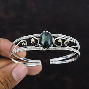 Può includere: Bracciale in argento con chiusura a cerniera, decorato con una pietra di labradorite blu scuro incastonata in un design a filigrana d'argento.
