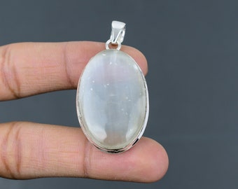 May include: A silver pendant with a white oval moonstone gemstone. The pendant is approximately 1 inch in length.