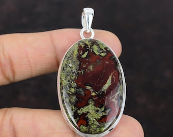 Può includere: Un ciondolo di forma ovale con una pietra rossa, verde e marrone incastonata in una cornice d'argento. La pietra presenta un motivo unico e vorticoso.