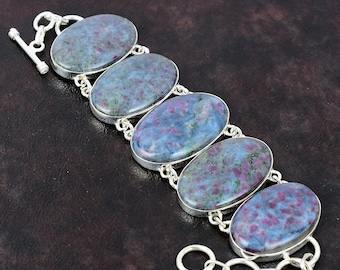 May include: A silver bracelet with six oval-shaped blue and pink gemstones. The bracelet has a toggle clasp.