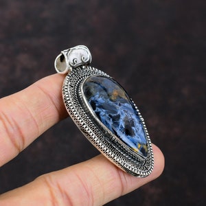Pu&ograve; includere: Ciondolo in argento con una pietra di occhio di tigre blu e oro incastonata in una cornice d'argento dettagliata.