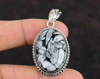 May include: A silver pendant with a black and white fossilized stone set in an oval shape. The pendant has a detailed silver border.