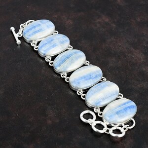 May include: A silver bracelet with six oval-shaped blue and white striped stones. The bracelet has a toggle clasp.