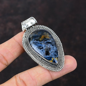 Pu&ograve; includere: Un ciondolo d'argento con una pietra di occhio di tigre blu e oro. Il ciondolo ha la forma di una lacrima ed &egrave; decorato con un bordo in argento dettagliato.