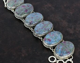 May include: A silver bracelet with six oval-shaped blue and pink gemstones. The bracelet has a delicate filigree design and a clasp.