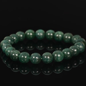 May include: A green gemstone bracelet with round beads. The bracelet is on a black background.