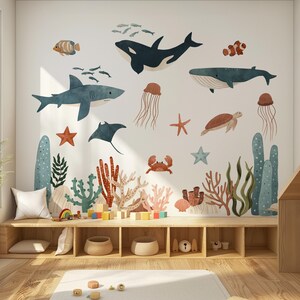 May include: A children's room decorated with a wall mural of marine life, such as whales, sharks, and jellyfish. The room includes wooden shelves, a rug, and wooden toys, creating a fun and educational space for children.