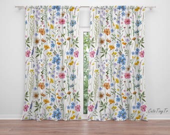 May include: White floral curtains with a repeating pattern of colorful wildflowers. The design includes pink, yellow, blue, and purple flowers with green stems and leaves. The curtains are hanging in front of a window, with a wooden floor.