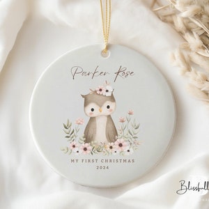 May include: A white ceramic Christmas ornament with a brown owl illustration, pink flowers, and the text "Parker Rose My First Christmas 2024".