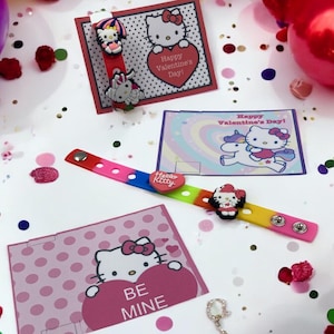 Könnte beinhalten: Eine farbenfrohe Hello Kitty-Themenanordnung zum Valentinstag. Sie zeigt ein Regenbogenarmband, Karten mit herzförmigen Botschaften und dekorative Charms. Auf den Karten steht "Happy Valentine's Day!" und "Be Mine."