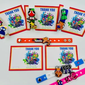 May include: Rainbow Friends themed party favors with colorful thank you cards, bracelets, and character charms. The cards feature a group of cartoon characters with the text "Thank You" and "For Making My Birthday Special!" The bracelets are made of silicone and have the Rainbow Friends logo. The charms are made of plastic and feature different characters from the game.