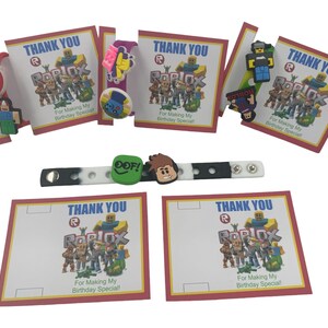 May include: A set of six Roblox-themed thank you cards with a red and white border. Each card features a different Roblox character and the text "Thank You" and "For Making My Birthday Special!" in red and white text. The cards are accompanied by a black and white silicone bracelet with a Roblox character charm.