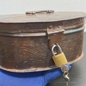 Caja de herramientas vintage de metal de la década de 1930 con forma ovalada y diseño floral, con cerradura y llave.