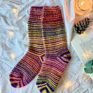 May include: A pair of colorful striped socks in shades of purple, yellow, orange, and pink. The socks are knitted and have a textured pattern.