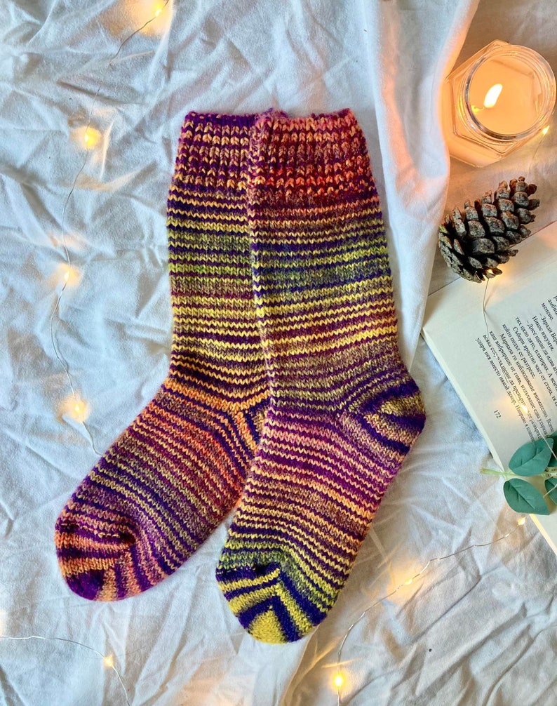 May include: A pair of colorful striped socks in shades of purple, yellow, orange, and pink. The socks are knitted and have a textured pattern.