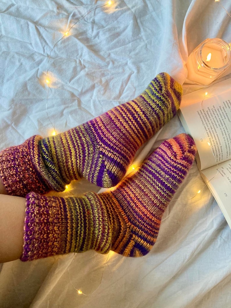 May include: A pair of colorful striped socks in shades of purple, orange, yellow, and green. The socks are made of a soft, fuzzy material and are perfect for keeping your feet warm in the winter.