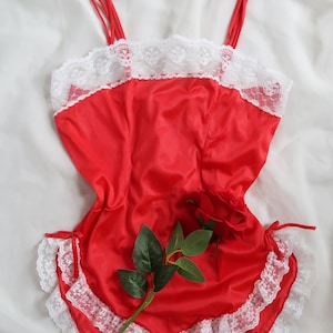 May include: Red satin lingerie with white lace trim and a red rose.