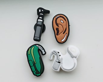 Puede incluir: Cuatro tipos diferentes de audífonos, incluyendo un audífono verde detrás de la oreja, un audífono blanco en la oreja, un modelo de oreja marrón y un otoscopio negro.